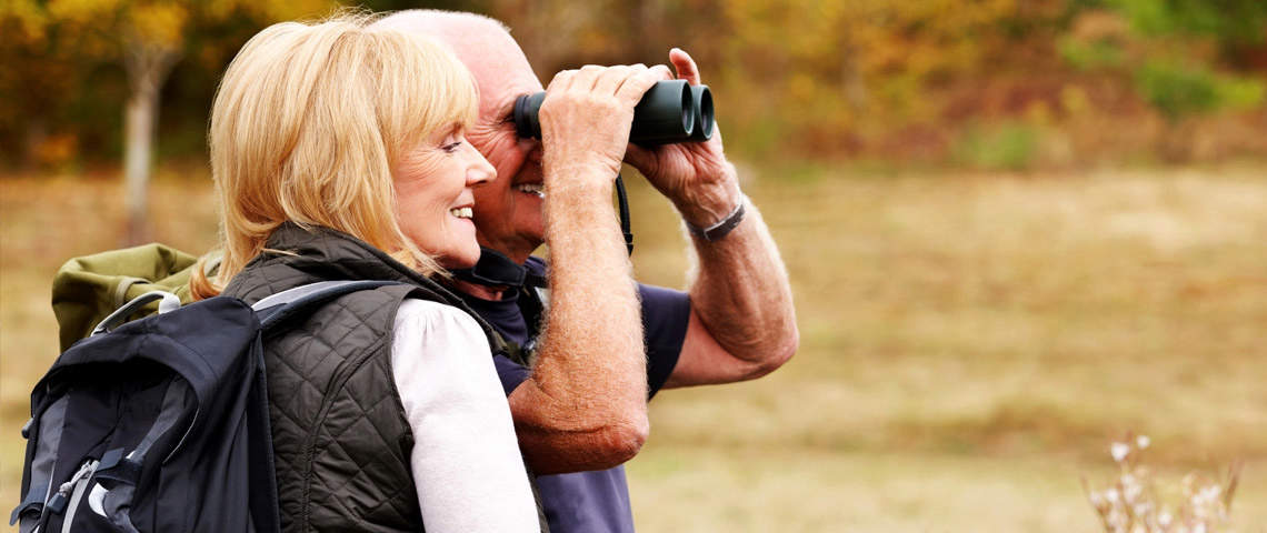 Man and woman birdwatching with binoculars