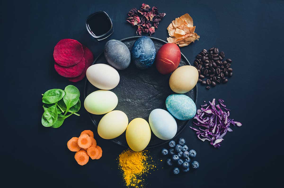 A circle of naturally dyed eggs with the corresponding kitchen item used for the dye.